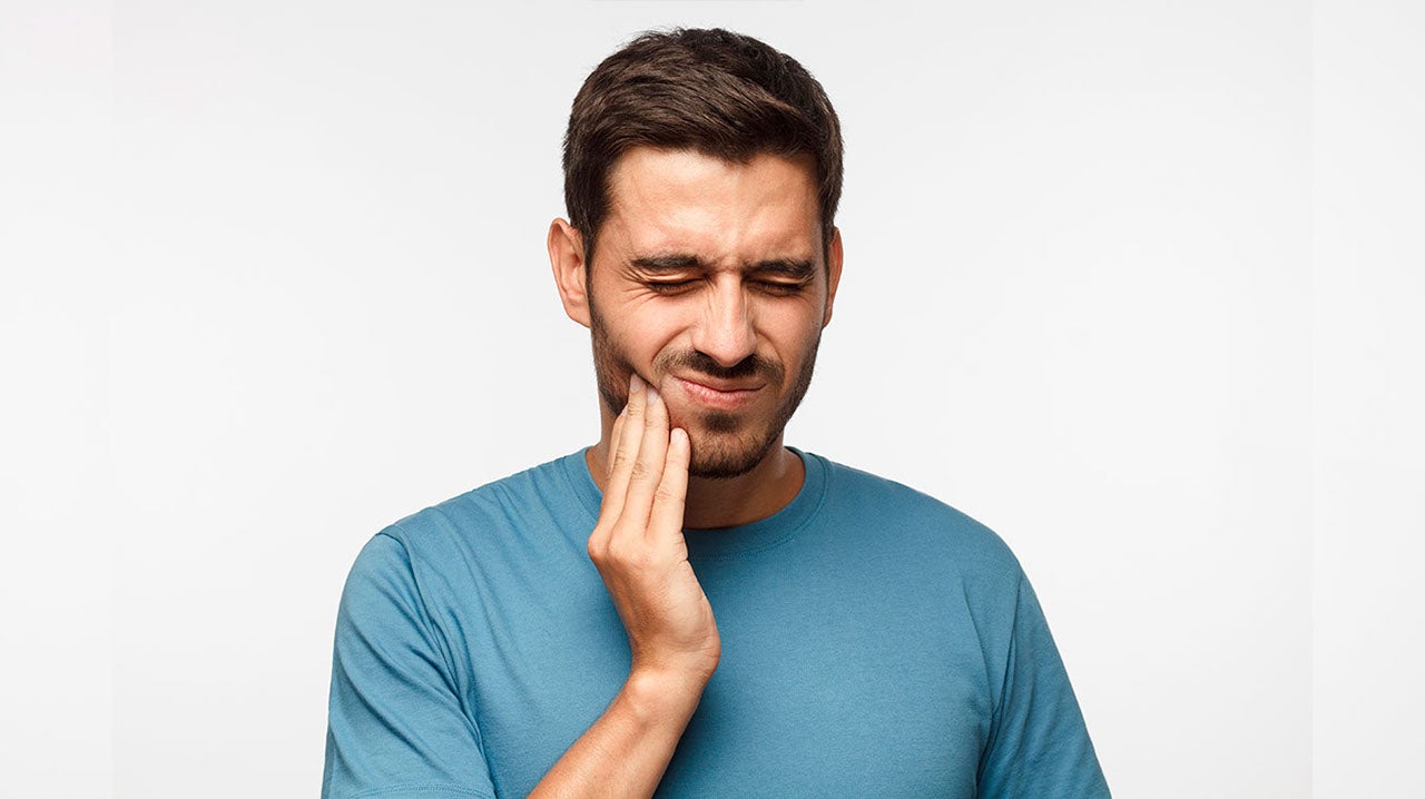 Man holding hand on mouth suffering from toothache pain white background
