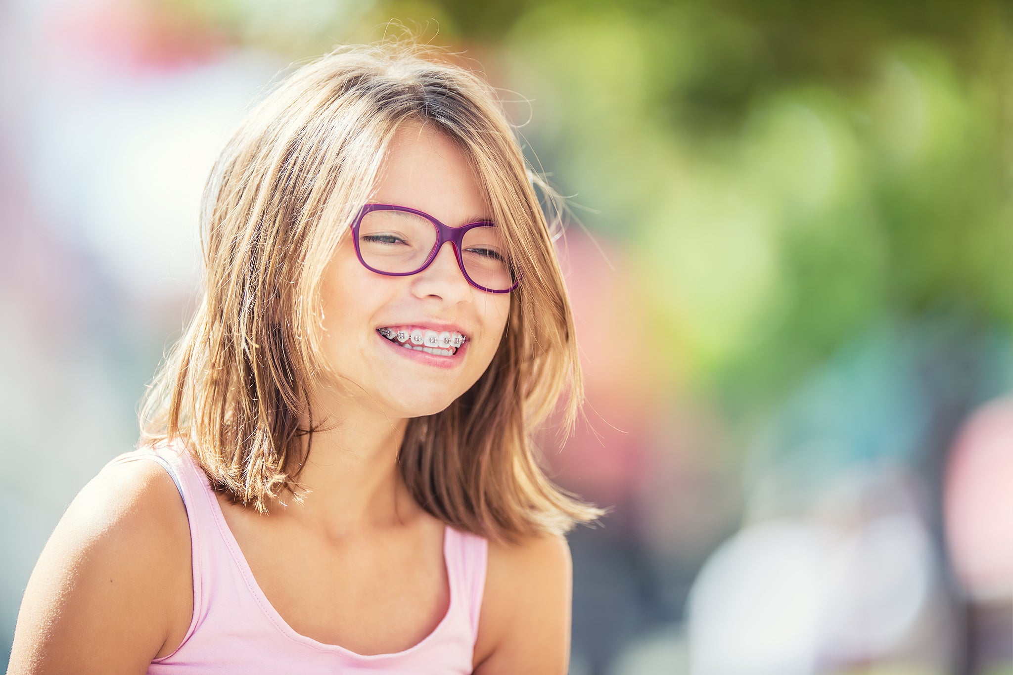 Happy smiling girl with dental braces and glasses. Young blond kid wearing teeth braces and purple glasses