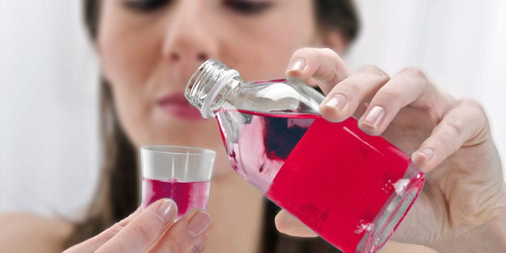 Woman pouring blue mouthrinse mouthwash 