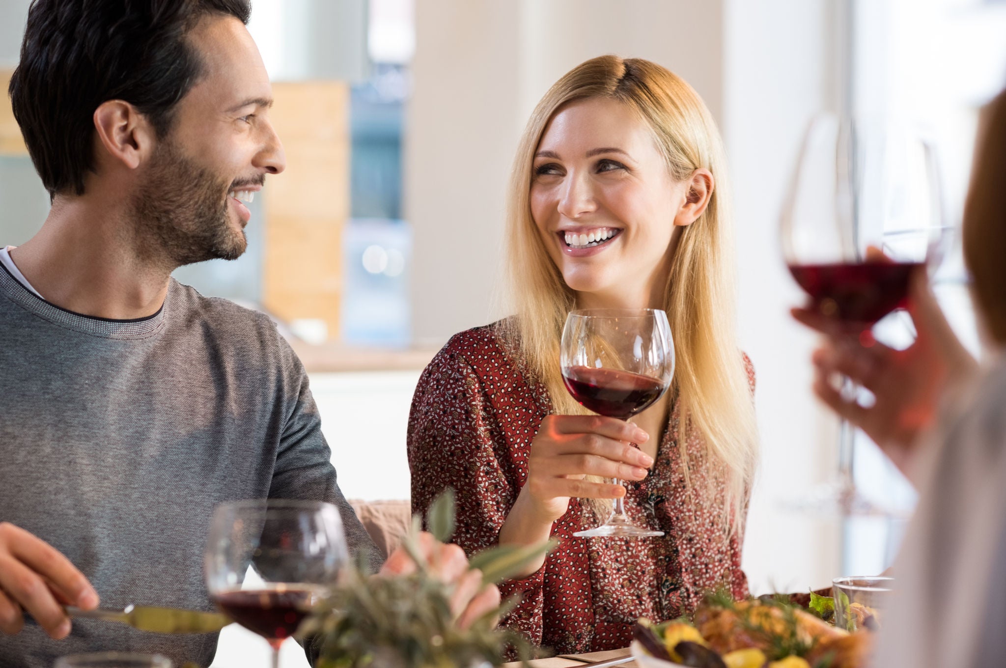 Laughing-friends-having-dinner-and-drinking-a-glass-of-red-wine