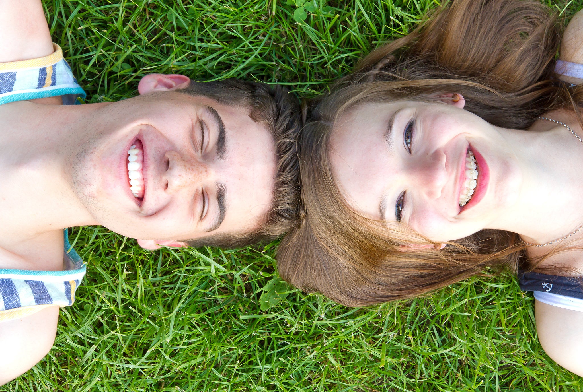 Happy-couple-lying-in-grass-and-the-girl-smiling-with-her-braces