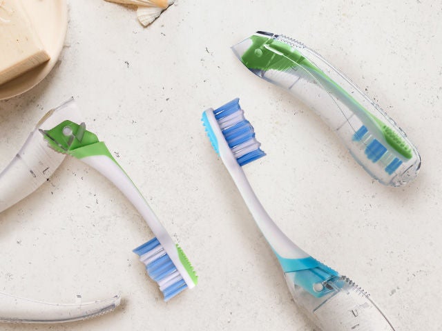 GUM Travel toothbrush in two colors: the blue one lying flat and the green one folded