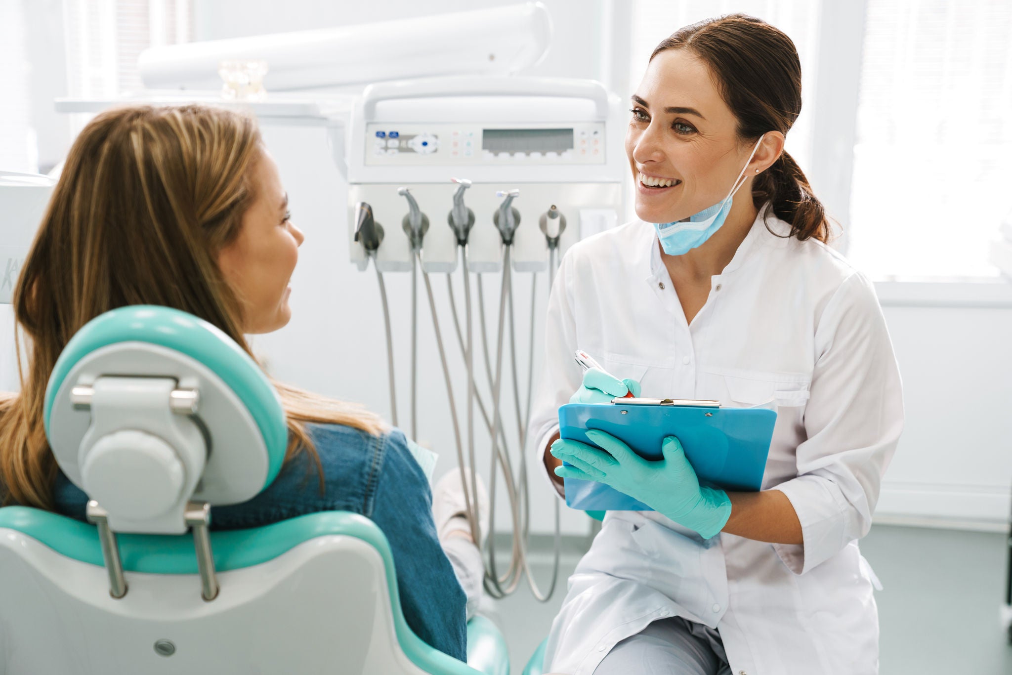European mid dentist woman smiling while working with patient in dental clinic