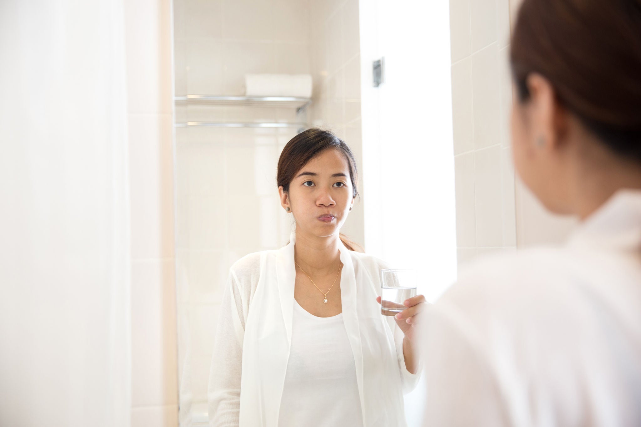 A portraiyt of an Asian young woman gargle on her mouth after tooth brushing