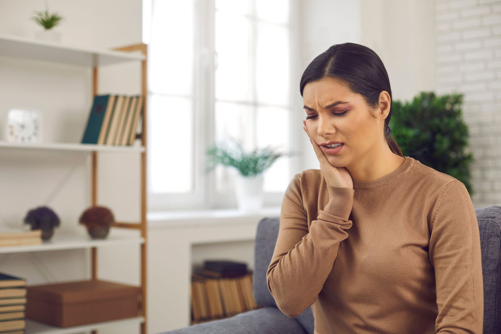 Unhappy-young-woman-suffering-from-toothache-and-touching-cheek