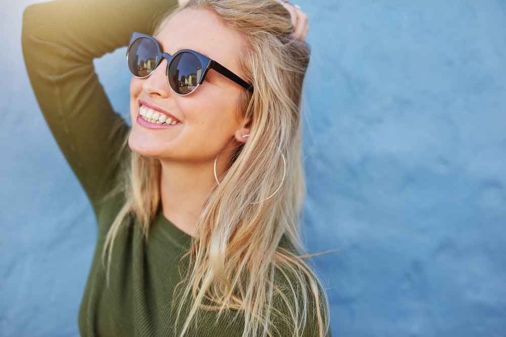 Woman-young-cheerful-sunglasses-against-blue