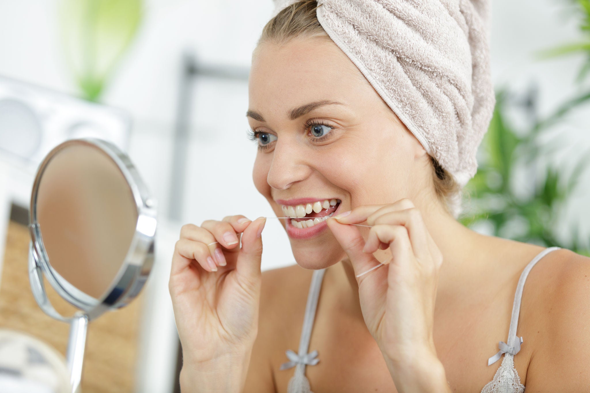 woman cleaning her teeth using dental floss