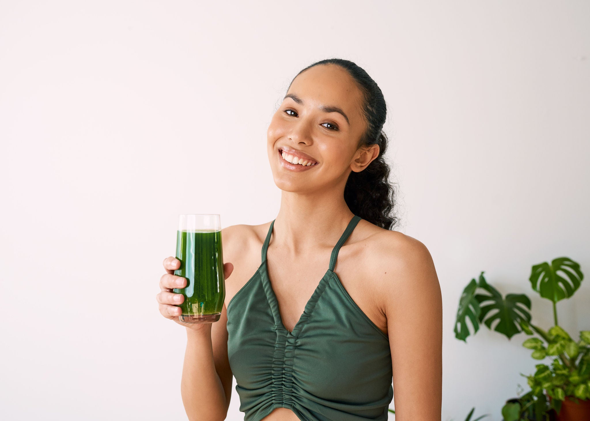 A beautiful multi-ethnic woman smiles with green juice - spinach, kale, vitamans. High quality photo
