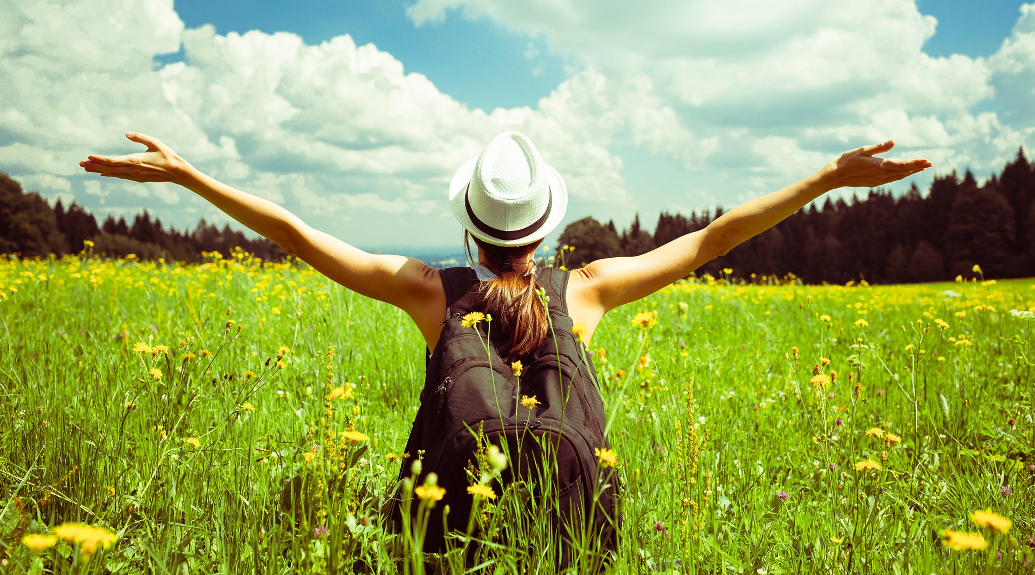 Woman seen from behind relaxing in a field enjoying outdoor nature
