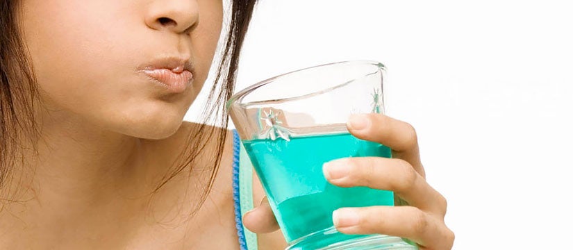 Woman rinsing mouth with green mouthwash white background