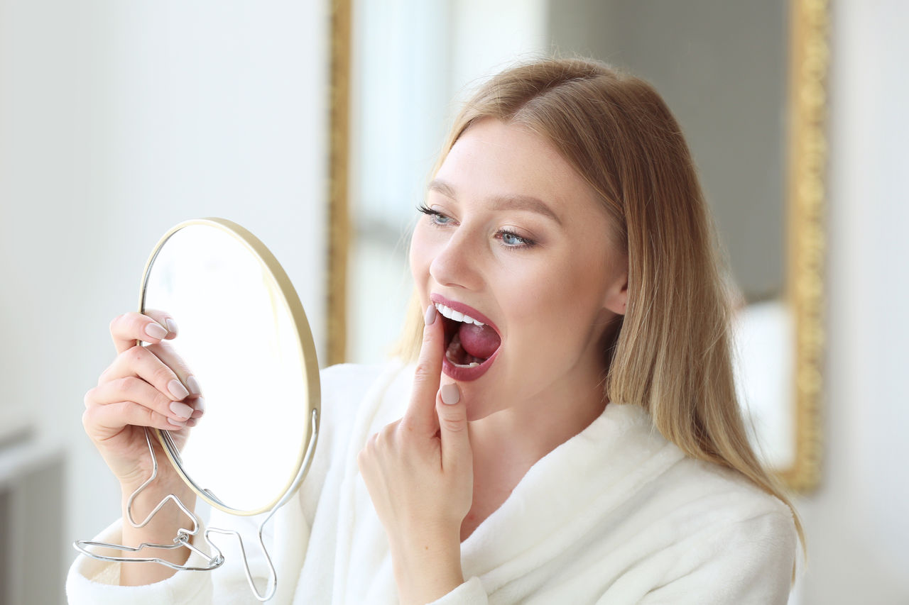 Woman checking whiteness of her teeth at home