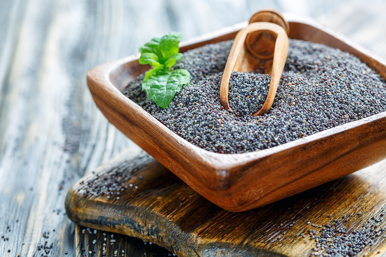 Poppy seeds and green mint in a bowl on old wooden table, selective focus mint leaf