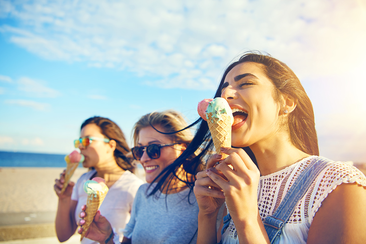 A group of women eating ice cream outside happy woman by the sea