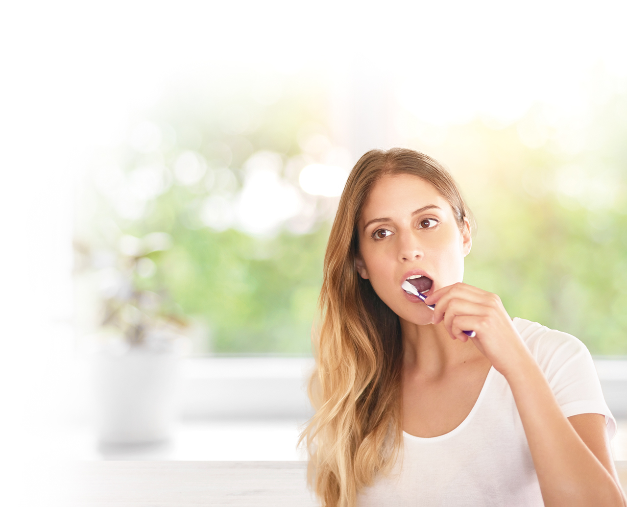 Young woman brushing her teeth in the bathroom white iStock-629079770