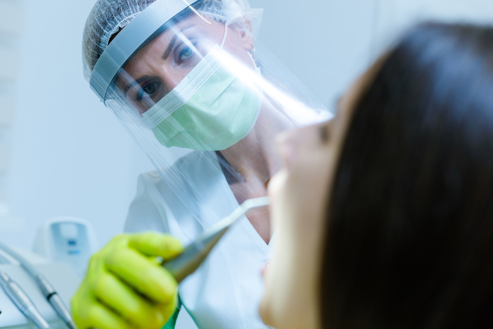 OCP-Dentist-woman-green-mask-facing-patient-in-chair
